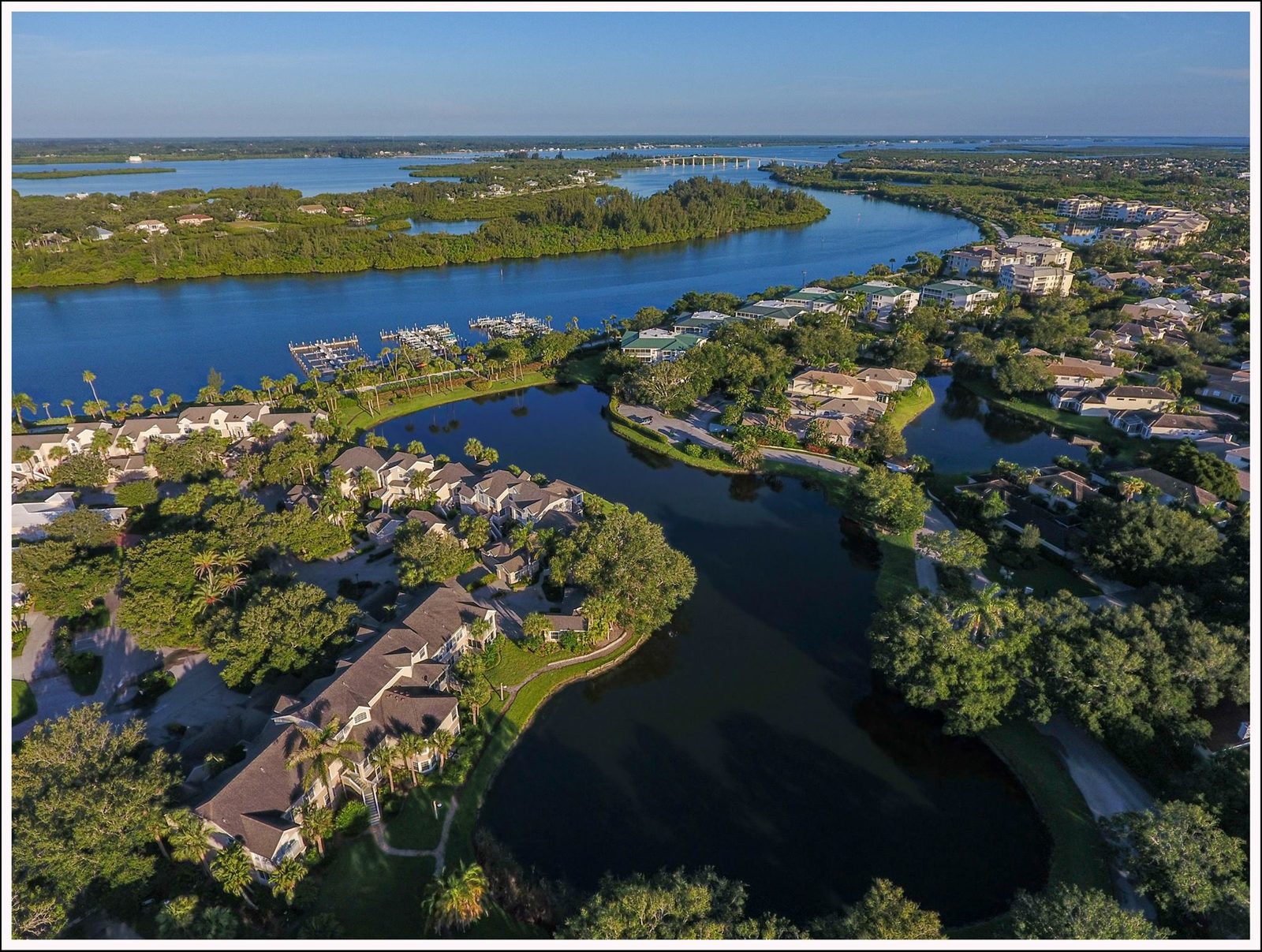 Aerial view of a Vero Beach barrier island club community along the Indian River Lagoon, with estate residences, a private marina, and the Atlantic beyond